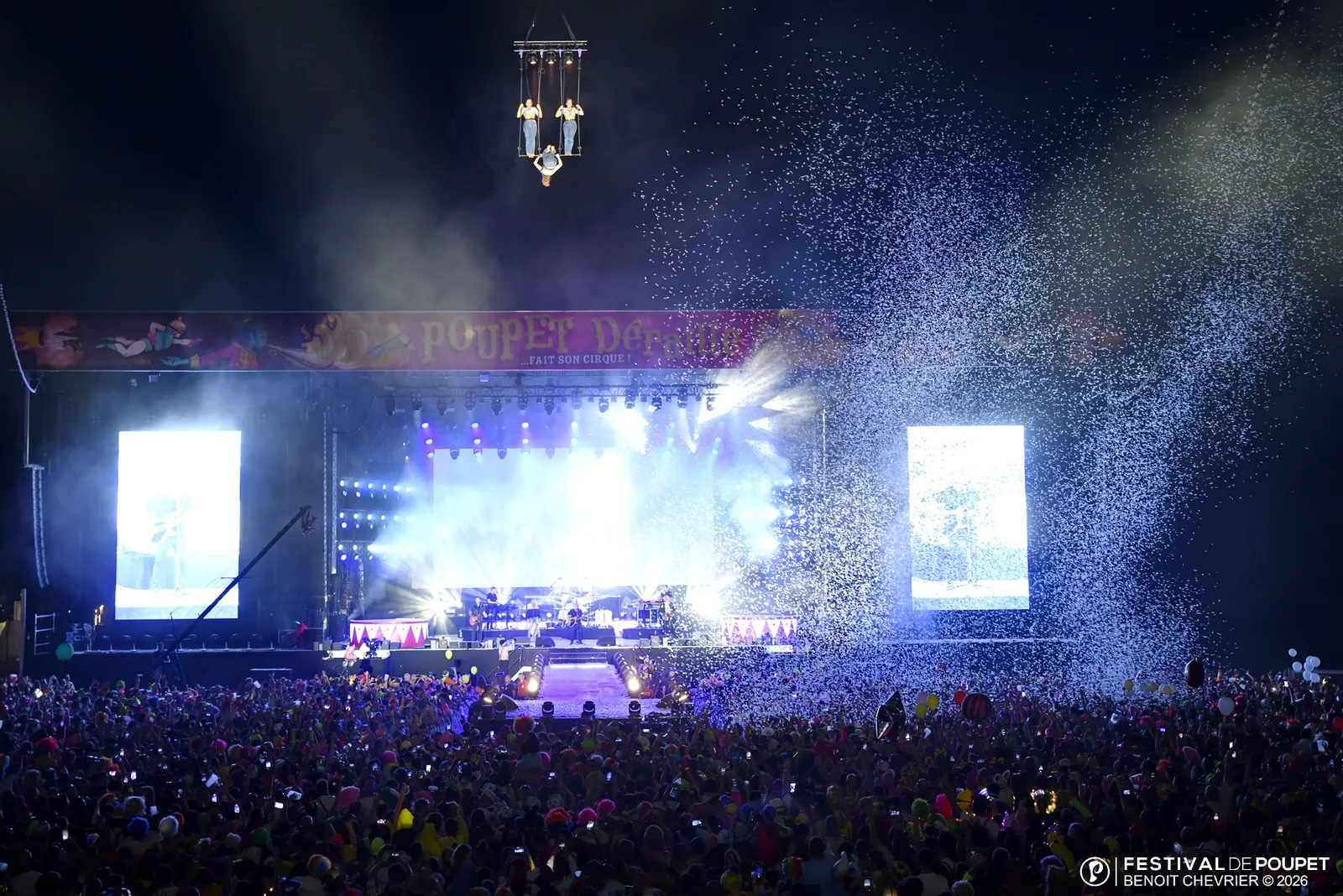 Des artistes suspendus au-dessus de la scène et de la foule du Festival de Poupet